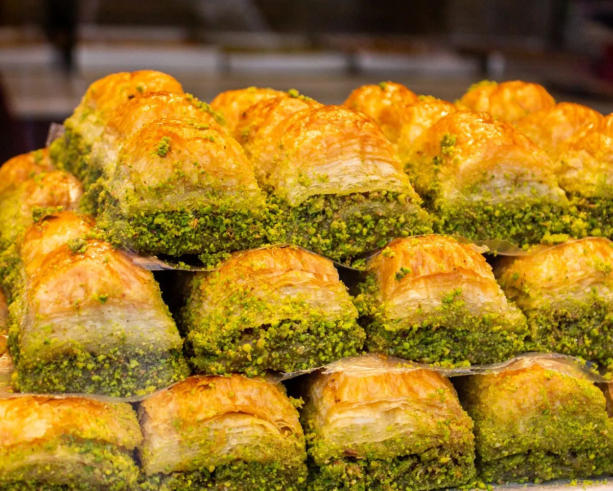 Rows of pistachio-topped baklava in a dessert display